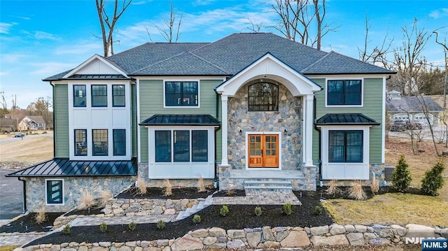 view of front of property with a standing seam roof, a shingled roof, stone siding, and metal roof