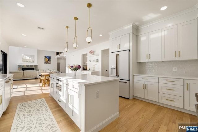 kitchen with high end fridge, light wood finished floors, light countertops, and a stone fireplace