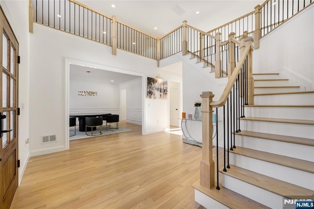 entryway with visible vents, stairway, a high ceiling, wood finished floors, and baseboards