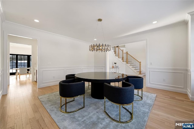 dining space featuring light wood-style flooring, stairway, crown molding, a decorative wall, and recessed lighting