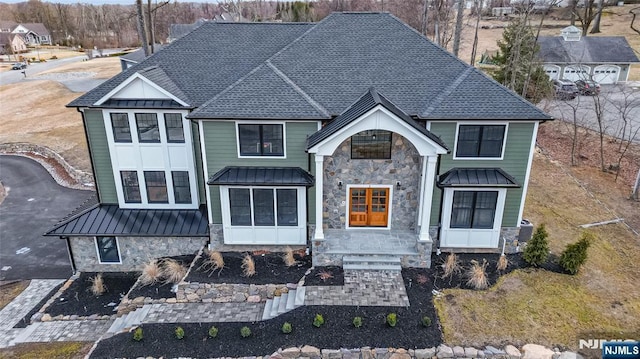 view of front of property featuring stone siding, roof with shingles, metal roof, and a standing seam roof