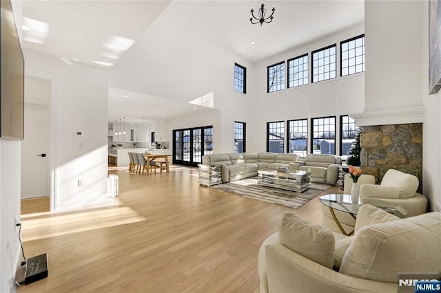 living area with a towering ceiling, light wood finished floors, a notable chandelier, and recessed lighting