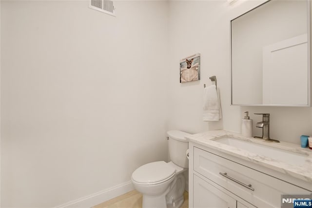 bathroom featuring toilet, vanity, visible vents, and baseboards