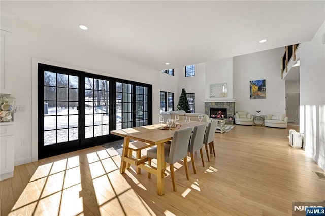 dining room with light wood-style floors, recessed lighting, a fireplace, and plenty of natural light