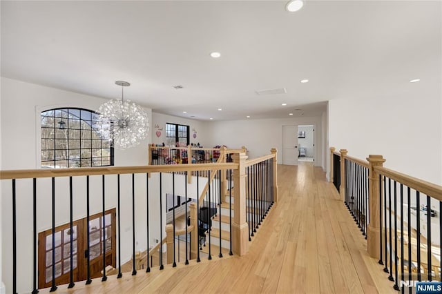 corridor featuring recessed lighting, visible vents, an upstairs landing, light wood finished floors, and an inviting chandelier