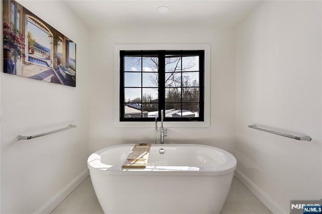 full bath featuring a freestanding tub and baseboards