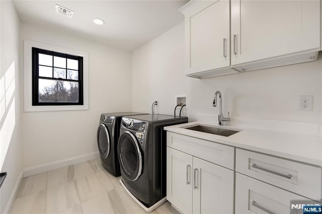 washroom with cabinet space, visible vents, washing machine and dryer, a sink, and baseboards