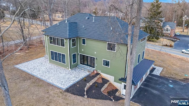 back of property featuring a shingled roof and a patio area