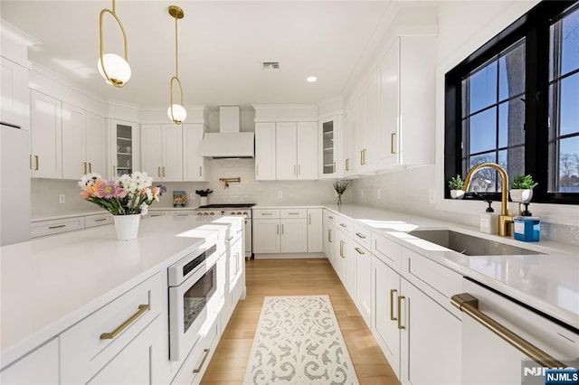 kitchen with a sink, visible vents, custom exhaust hood, built in microwave, and dishwasher