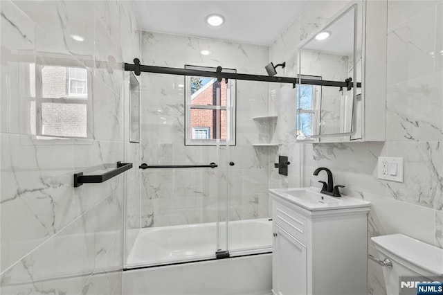 full bathroom featuring tile walls, vanity, toilet, and bath / shower combo with glass door