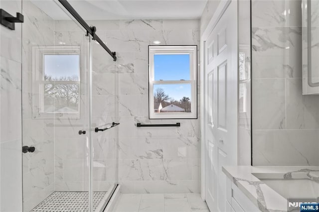 bathroom featuring marble finish floor, a stall shower, plenty of natural light, and a sink