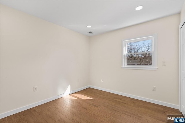 spare room featuring recessed lighting, wood finished floors, visible vents, and baseboards