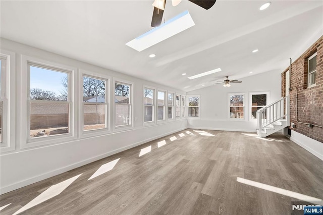 unfurnished sunroom featuring ceiling fan and lofted ceiling with skylight