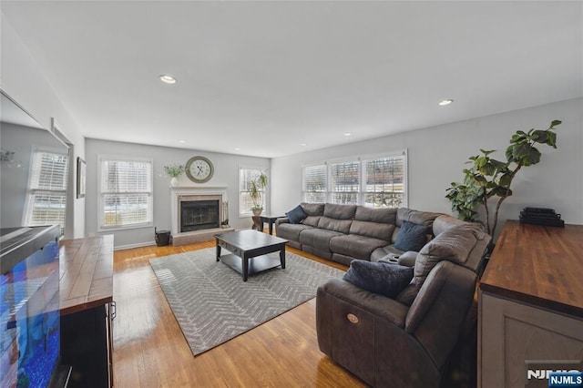 living area with recessed lighting, light wood finished floors, and a premium fireplace