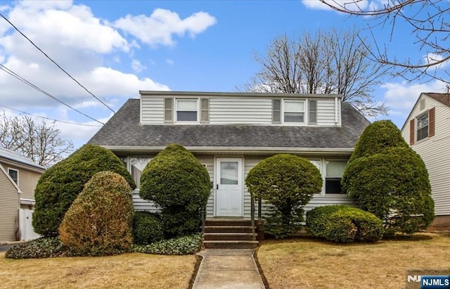 view of front of home with entry steps, a shingled roof, and a front lawn