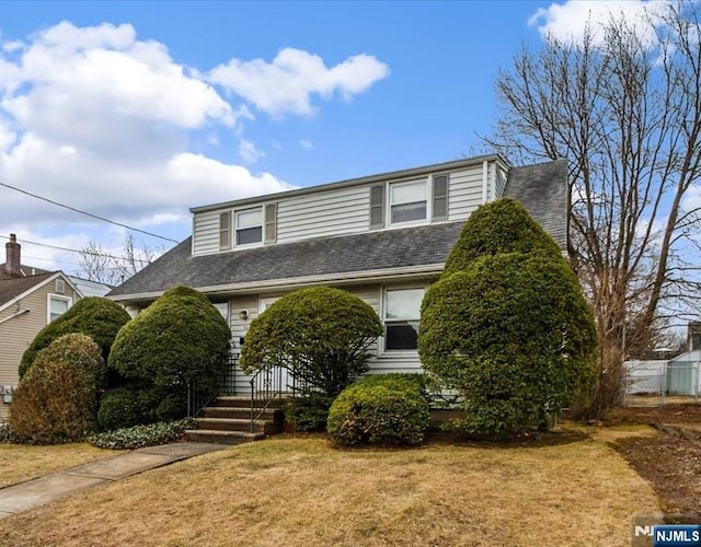 view of front of property featuring a shingled roof and a front lawn