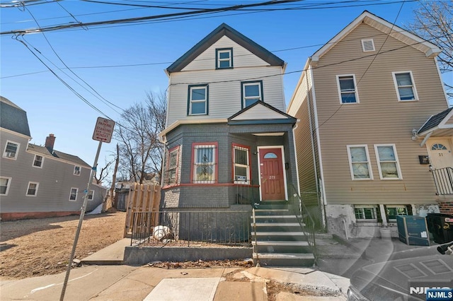 view of front of home with entry steps, fence, and brick siding