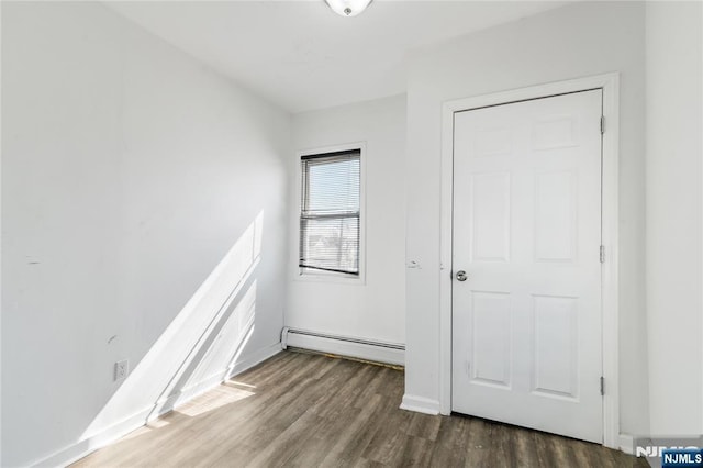 unfurnished bedroom featuring baseboards, baseboard heating, and wood finished floors