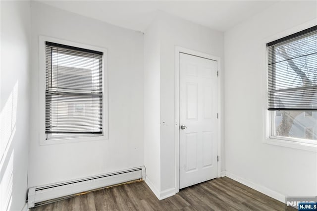 unfurnished bedroom featuring baseboards, baseboard heating, and wood finished floors