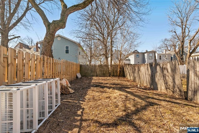 view of yard featuring central air condition unit, a fenced backyard, and a residential view