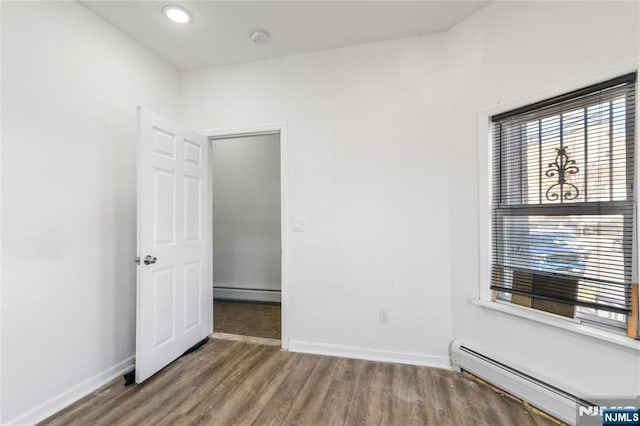 spare room featuring a baseboard heating unit, a baseboard radiator, wood finished floors, and baseboards