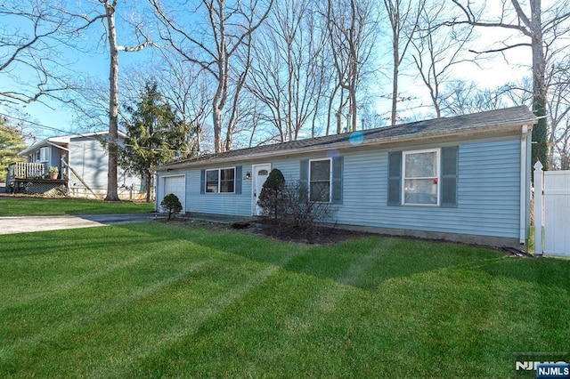 ranch-style house featuring a garage, driveway, a front yard, and fence