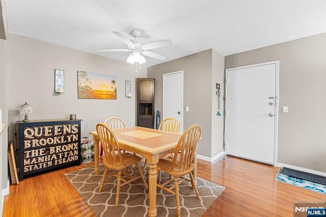 dining area with light wood finished floors, a ceiling fan, and baseboards