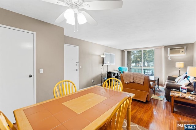 dining area with a ceiling fan, an AC wall unit, and wood finished floors