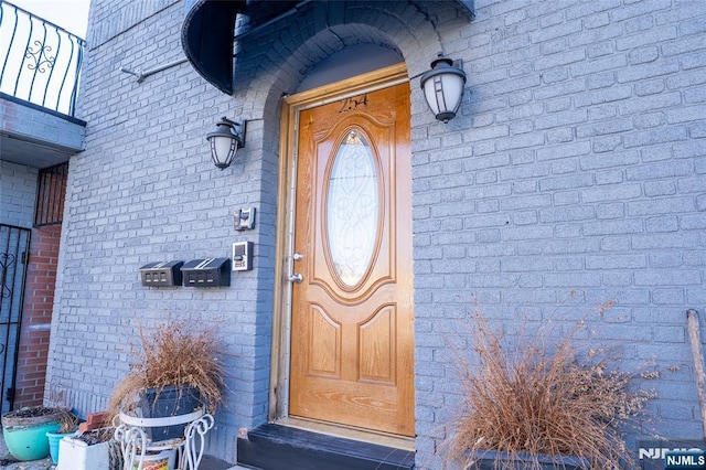 entrance to property featuring a balcony and brick siding