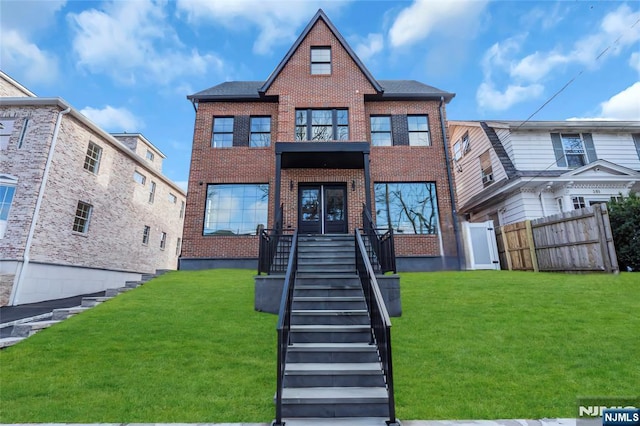 view of front facade featuring a front yard, stairway, fence, and brick siding