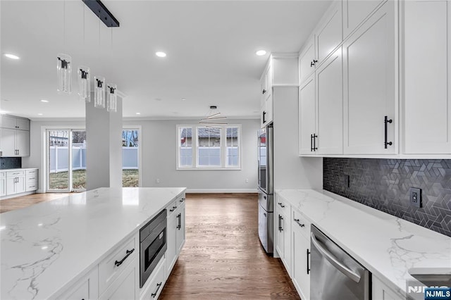 kitchen featuring white cabinets, decorative backsplash, appliances with stainless steel finishes, wood finished floors, and recessed lighting