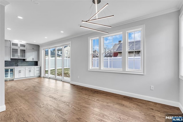 unfurnished living room featuring beverage cooler, baseboards, wood finished floors, and crown molding