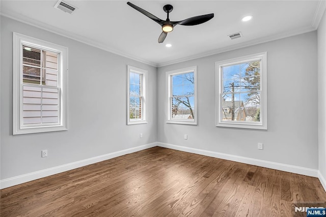 spare room featuring ornamental molding, wood finished floors, visible vents, and baseboards