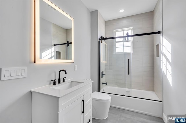 bathroom with vanity, toilet, and bath / shower combo with glass door