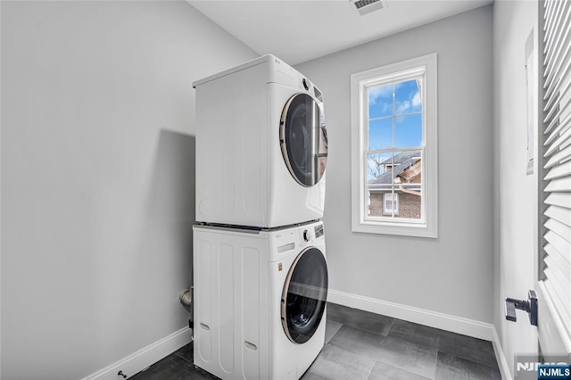 clothes washing area featuring laundry area, stacked washer / dryer, visible vents, and baseboards