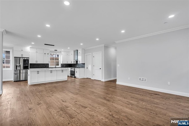 kitchen featuring decorative backsplash, open floor plan, a center island, stainless steel appliances, and crown molding