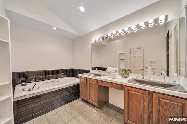 bathroom featuring a bath, double vanity, vaulted ceiling, and a sink