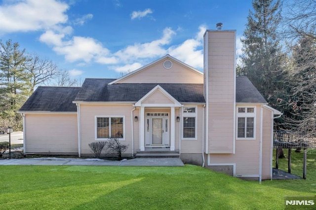 view of front of home featuring roof with shingles, a front lawn, and a chimney