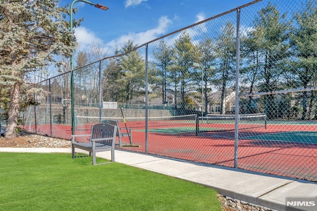 view of sport court featuring fence and a lawn