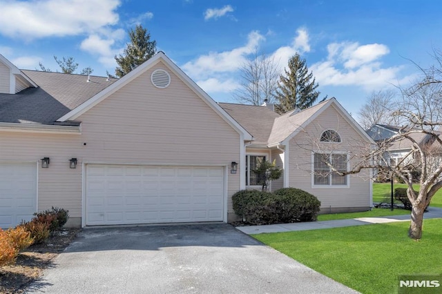 single story home featuring a garage, driveway, roof with shingles, and a front yard