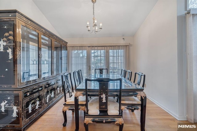 dining area featuring lofted ceiling, a notable chandelier, baseboards, and wood finished floors