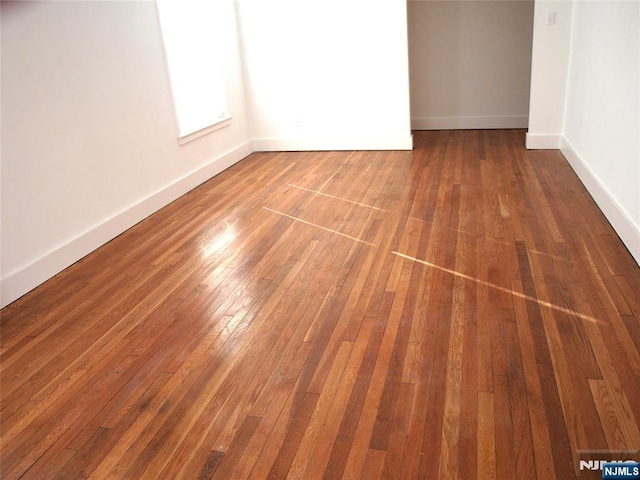 unfurnished room with baseboards and hardwood / wood-style floors