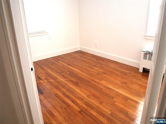 spare room with radiator, dark wood-style floors, and baseboards