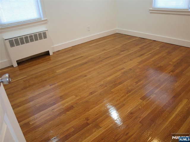 unfurnished room featuring light wood-type flooring, baseboards, and radiator heating unit