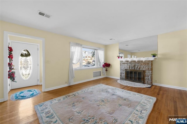 living area featuring baseboards, a fireplace, visible vents, and wood finished floors