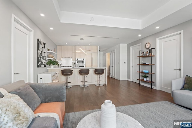 living room featuring baseboards, dark wood finished floors, a raised ceiling, and recessed lighting