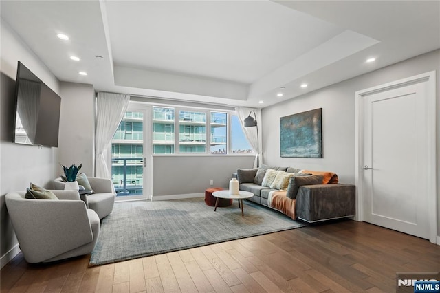 living area with a tray ceiling, baseboards, hardwood / wood-style floors, and recessed lighting