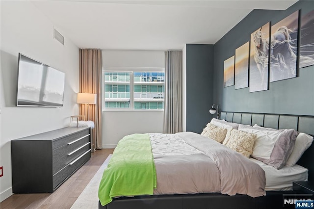 bedroom featuring light wood finished floors, visible vents, and baseboards