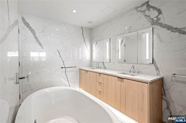 bathroom with recessed lighting, a freestanding tub, a sink, and double vanity