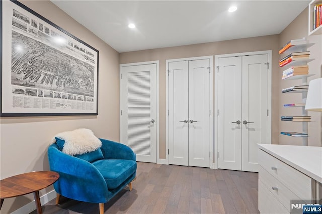 living area with baseboards, wood finished floors, and recessed lighting